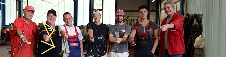 Sieben sich zur handwerklichen Arbeit präsentierende Männer